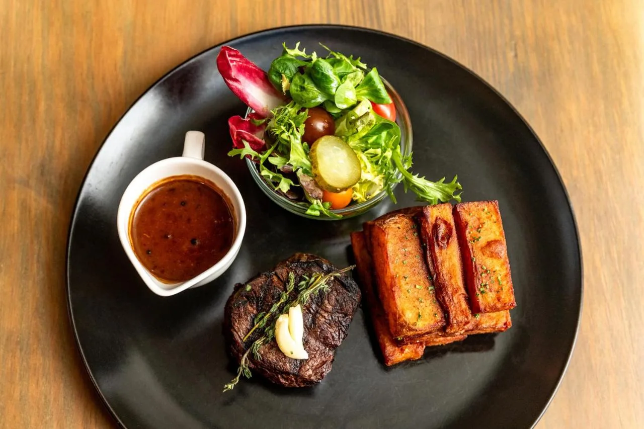 a black plate with a meal of meat and a salad at The Shankly Hotel in Liverpool