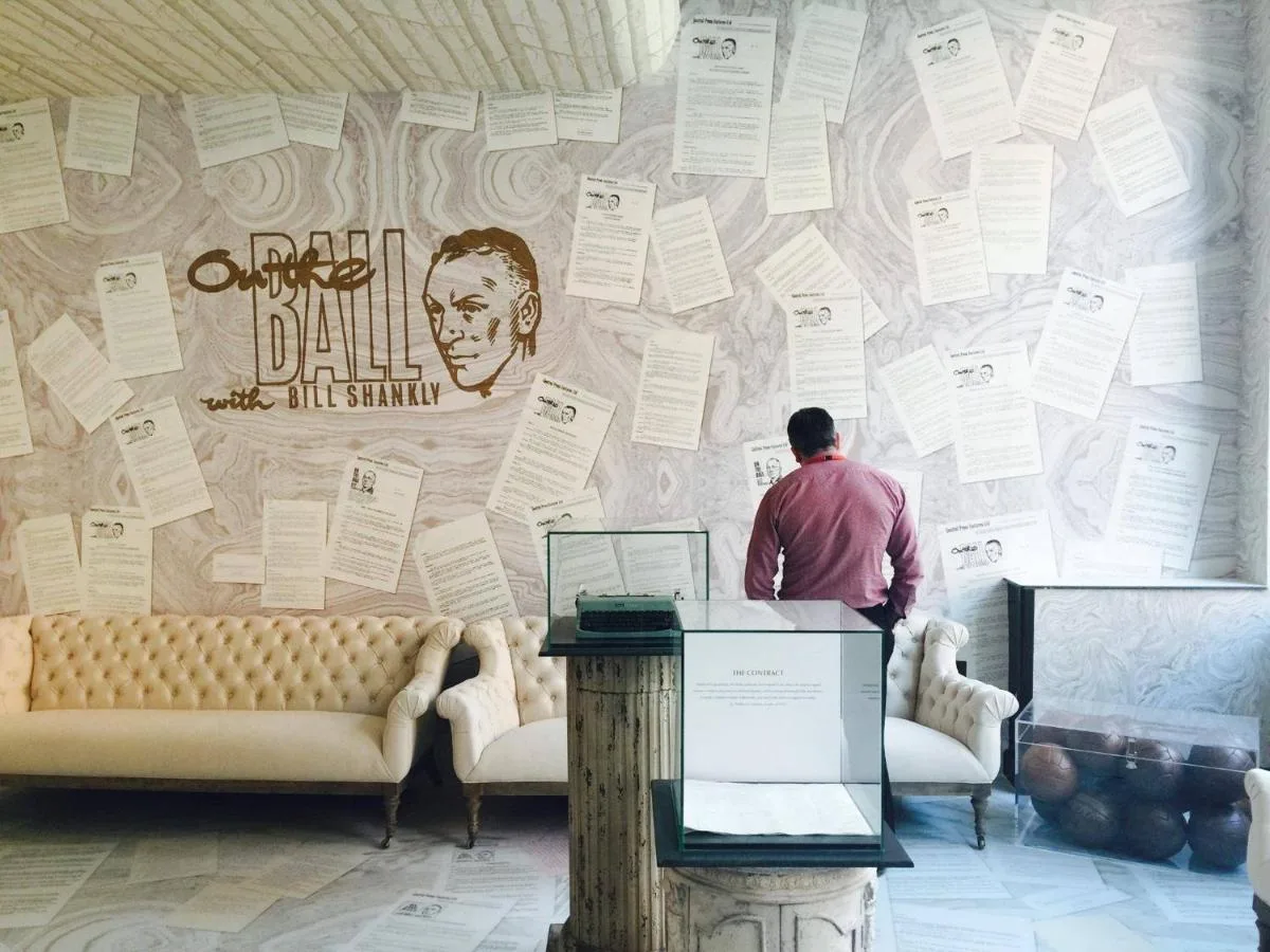 a man standing in front of a wall with posters at The Shankly Hotel in Liverpool